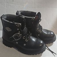 Side angle view of both black Harley Davidson biker boots with logo and buckle strap showing.