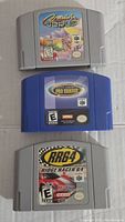 Three Nintendo 64 game cartridges arranged vertically showing front labels: Mario's Mario World (gray), Ready 2 Rumble Pro Shaker (blue), Ridge Racer 64 (gray).