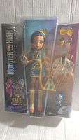 Front view photo of Monster High Cleo De Nile doll in packaging showing doll and accessories clearly.