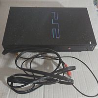 Side view focusing on power cord and AV hookup cable with red and white RCA plugs coiled in front of console.