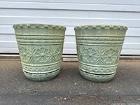 Front view of both vintage green Lawnware planters showing floral and geometric relief designs on the sides and scalloped rim edges.