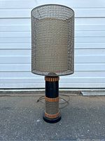 Full view of the lamp showing cylindrical cane shade and base details.