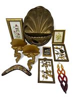 Full view of the lot showing various gold wall decor items including framed metal floral art, a large shell-shaped piece, Syroco wood shelves, floral fan, small paintings, and braided resin wall hanging.