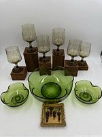 Six smoky grey Libbey Tawny Accent wine glasses with twisted stems, displayed alongside green pinched glass bowls and candlesticks.