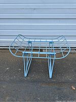 Full front-angle view of the light blue wrought iron patio ottoman showing grid seat and curved edges