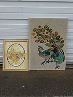 Full view of both framed art pieces: fabric embroidery with peacock and framed bird art print side by side.