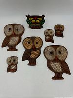 Overhead view showing all seven owl items and the colored owl napkin holder on a white background.