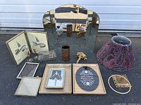 Wide shot of all items including frames, folding mirror, paisley lampshade, decorative foot sculpture, candle holder, and small brass items