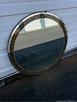 Full front view of large round mirror showing gold decorative inner frame and beveled mirror border