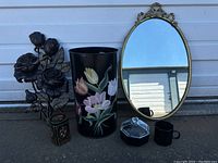 Photo showing the full lot with floral trashcan, metal rose sculpture, oval mirror, crystal lidded dish, and creamer with sugar containers.
