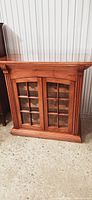 Full view of custom solid mahogany wine cabinet showing glass paneled double doors and fluted column details on corners.