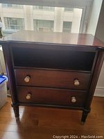 Front view of mahogany nightstand showing two drawers with silver-tone knob handles and open compartment above.