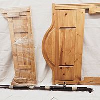 View of knotty pine wooden footboard and headboard side by side with metal bed rails below.