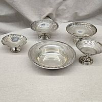 All six pieces together: one shallow bowl front center, five footed tazzas arranged behind and beside bowl