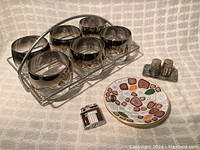 Full lot including six smoked mirrored Old Fashioned glasses in chromed wire holder, mosaic ceramic plate, brown enamelled vintage lighter, and silvertone abalone salt and pepper shakers on tray.