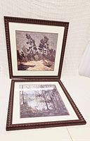 Two framed and matted prints placed on a white surface, showing texture and color of the artwork in detailed dark frames with ornate edges.