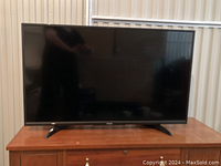 Front view of Toshiba 43-inch TV showing screen and legs on a wooden cabinet.