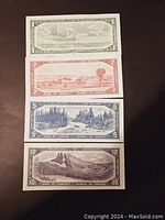Four Canadian paper bills on black background showing back side with landscapes