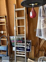 Photo showing the aluminum extension ladder standing upright indoors with various items around it.