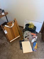 Overall view of the easel, paint supplies, bags, sketchbooks, and paper pads arranged on floor