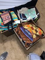 Photo showing two storage bins filled with assorted fabric and colorful bags including striped, patchwork, and printed patterns with handles visible