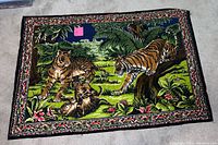 Photo showing colorful tapestry with three tigers in a jungle scene with detailed greenery and flowers surrounding them, laid flat on floor