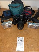 Three Canon cameras displayed with four camera cases on a brown surface.