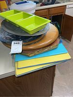 Stacked kitchen items including multiple cutting boards and trays on a kitchen counter.