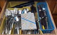Kitchen drawer with organized eating utensils including forks, spoons, knives, and some kitchen tools.