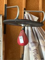 Speed bag mounted on a black rotating platform suspended from a metal frame attached to garage wall.