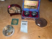 Photo showing all items together: iron balls in decorated box, carved decorative piece, coins in container, bronze coin, and metal plate.