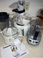 Photo showing Cuisinart food processor, citrus juicer, blender parts, and other kitchen appliances