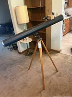 Full view of the large black tube telescope on a wooden tripod, showing overall structure and condition.