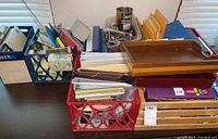 Photos of assorted office supplies including folders, papers, envelopes, stapler, trays, and crates on table.