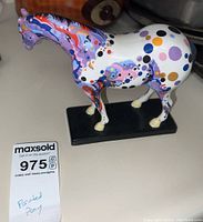 Front-left angle of the painted pony showing abstract colorful design and chipped ears.