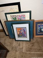 Photo showing the front view of all six picture frames with visible art prints, arranged overlapping on carpeted floor.