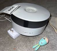 White round butterfly crystal diffuser on carpet with attached power cord and small blue rabbit keychain placed beside it.