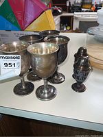 Four Reed & Barton sterling silver goblets with one sterling sugar caster on countertop