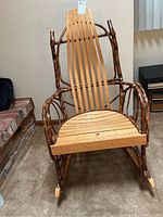 Full front view showing design with light oak slat seat and backrest and darker curved oak frame and armrests.