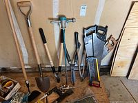 Photo shows a variety of yard tools including shovels, hand pruners, saws, a sprayer nozzle and gloves.