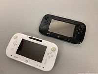 Black and white Nintendo Wii U Gamepads placed side by side showing front view