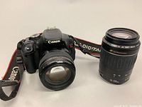 Front view of Canon EOS Rebel T3i with lens attached and separate 55-200mm lens to right