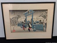 Full view of the framed woodblock print showing the complete snowy scene with three women near the torii gate.