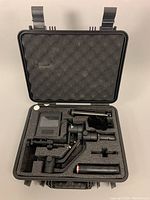 Opened hard case showing the camera stabilizer and several accessories arranged in foam compartments.