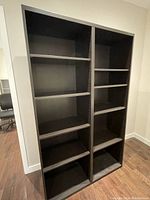 Two views of a black wood grain bookcase with multiple adjustable shelves in two vertical sections, showing overall appearance and shelving configuration.