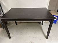 Black wooden rectangular table with four legs in a room, front view.