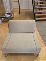 Front view of light beige wool fabric chair with chrome legs, showing removable cushions.