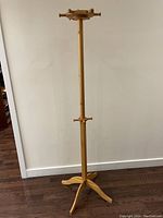 Full view of the wooden coat hanger stand showing the base, central pole, and top hooks.