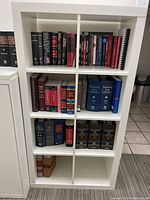 Front view of white IKEA cubicle shelf unit filled with various books showing shelf layout and condition.
