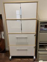 Front view of the office filing cabinet unit showing two upper storage compartments with closed doors, two lower filing drawers with locks, all on wheels.